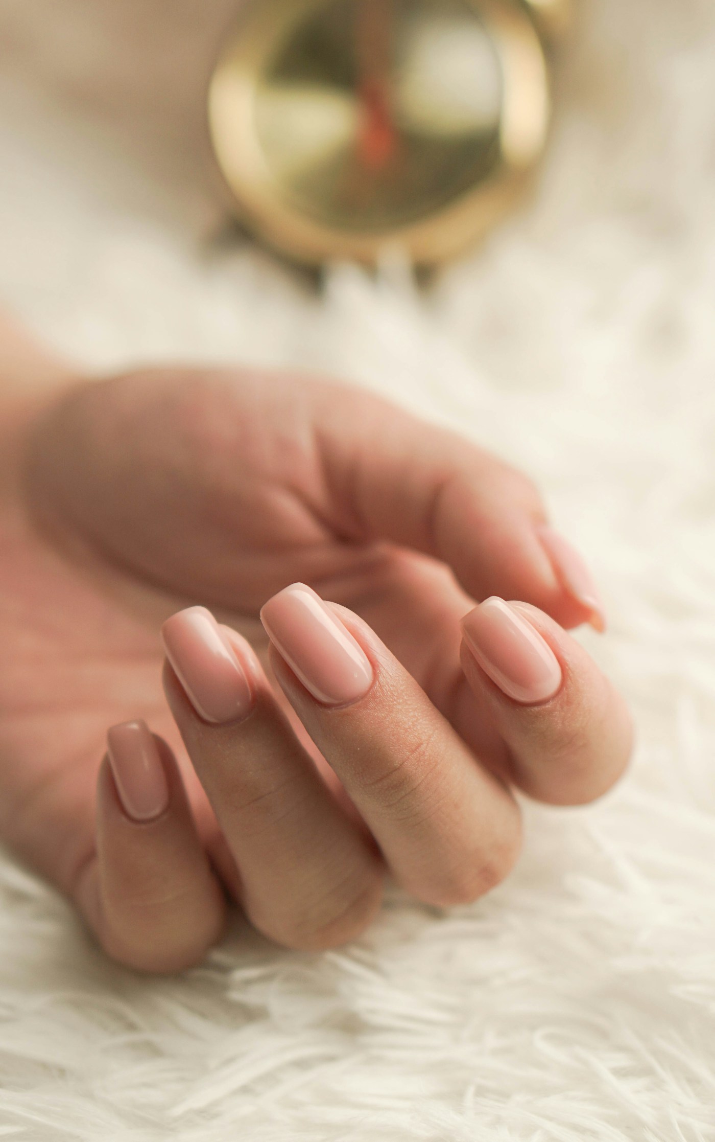 Mãos com unhas em tom nude rosado, esmaltação delicada